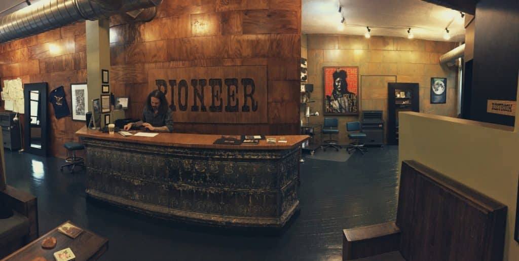 front desk at pioneer tattoo studio with a wooden background and chairs in the back