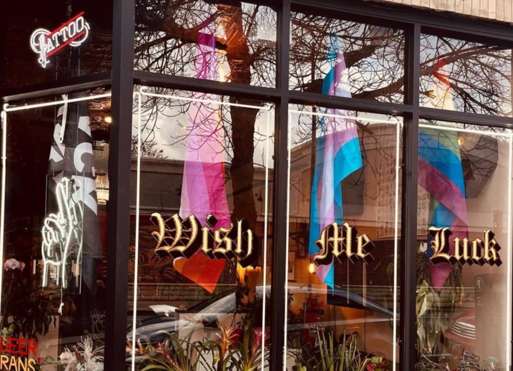 Exterior of Wish Me Luck Tattoo shop in Chicago shows store name painted on glass windows