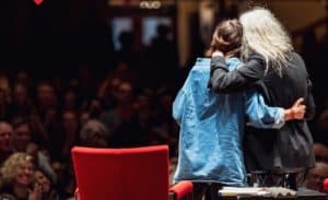 Photo shows two people embracing on stage as they give a talk at the Chicago Humanities Festuval