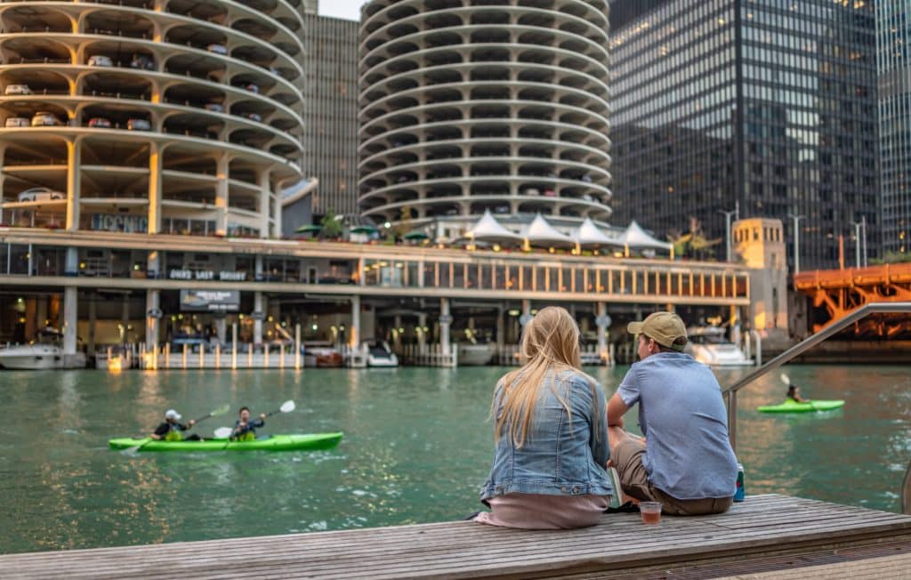 Image showing two people sat on the Chicago Riverwalk watching the architecture and people kayaking down the Chicago River in September