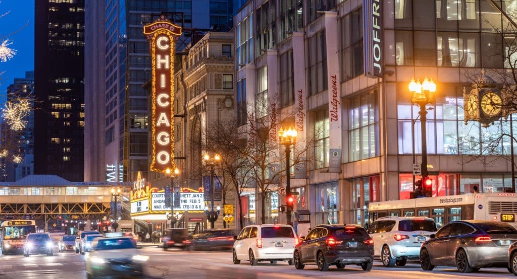 Photo of cars driving through downtown Chicago and past the Chicago Theatre on a winter's night in Chicago
