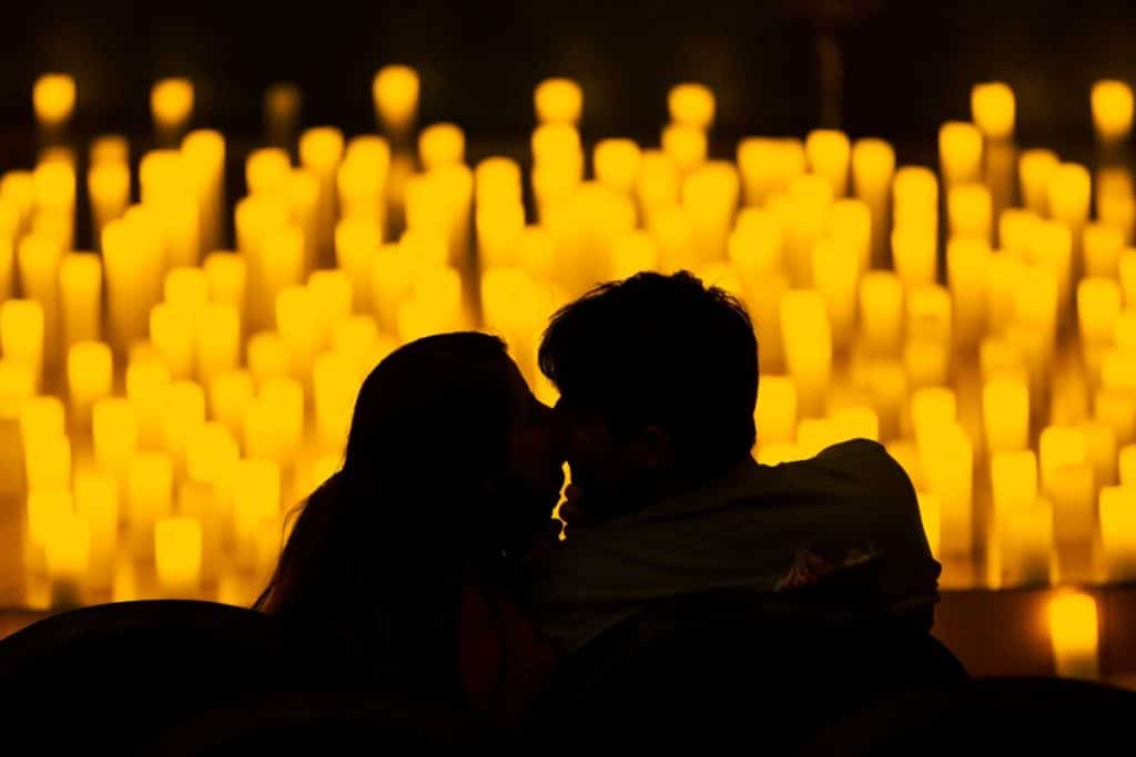 Silhouette of two people kissing with blurred candles in the background