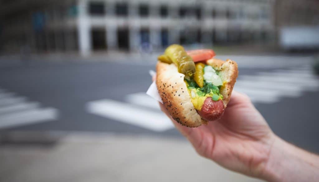 somebody holding a Chicago-style hotdog on the streets of Chicago