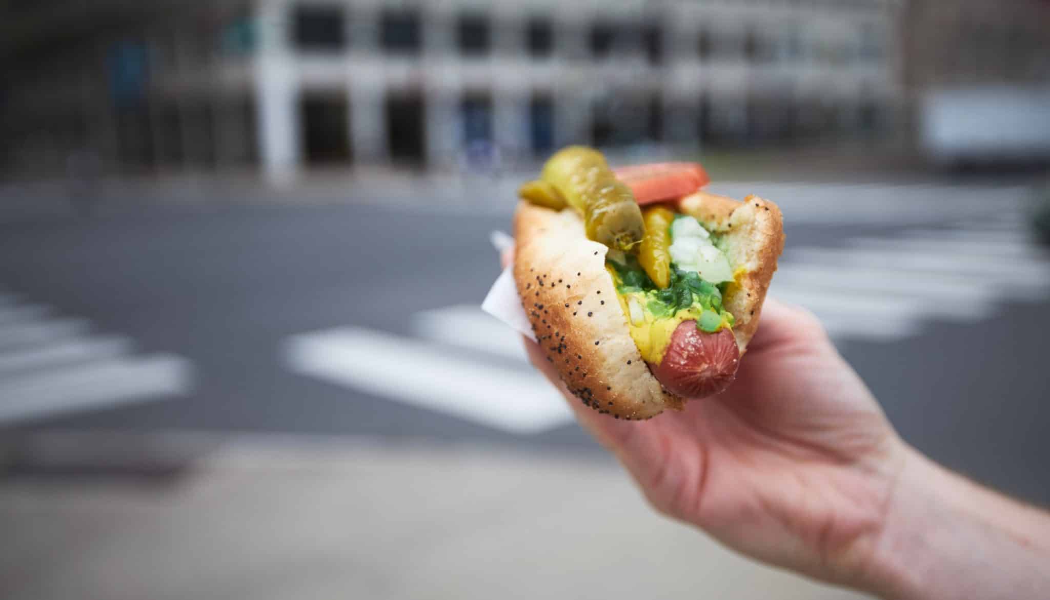 Photo of somebody holding a Chicago-style hotdog on the streets of Chicago