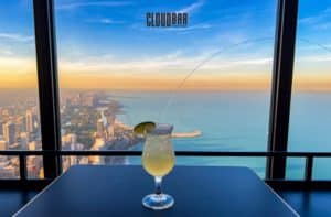Photo of a cocktail on a table in front of a stunning view of the city of Chicago from the new Chicago CLOUDBAR