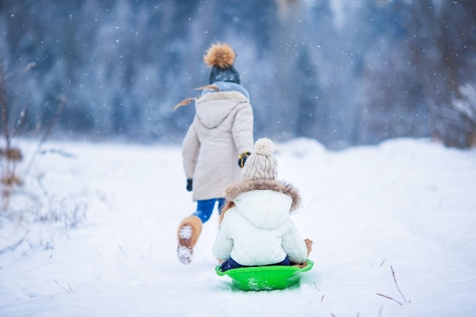 Two children sledding in the winter
