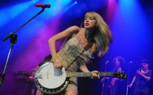 Taylor Swift performing on stage holding a guitar
