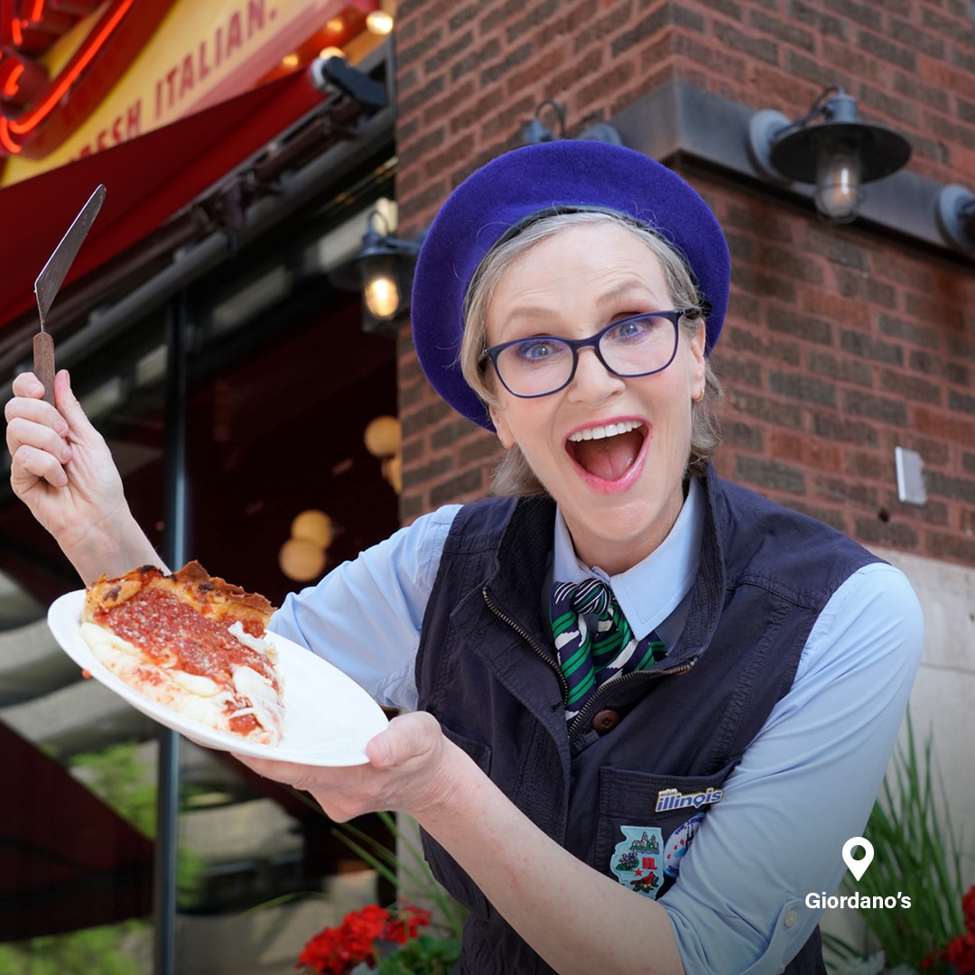 Jane Lynch holding a slice of pizza