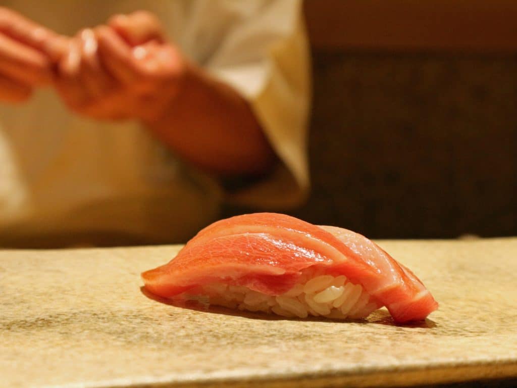 tuna nigiri roll being handmade by chef