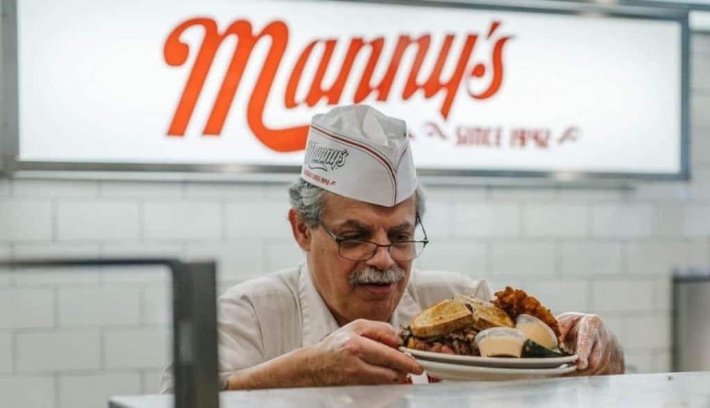 Person serving a sandwich at Manny's