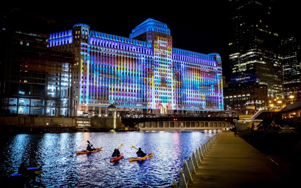 Image showing people kayaking down the Chicago River past the Merchandise Mart showing Art on the Mart projections by Charles Atlas