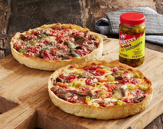 Two varieties of pizza seen on a wooden block