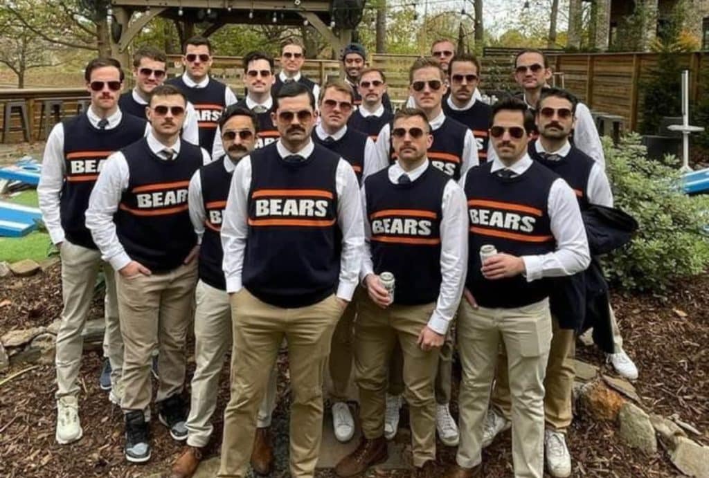Group of guys dressed up in sweater vests, tan pants, and sunglasses