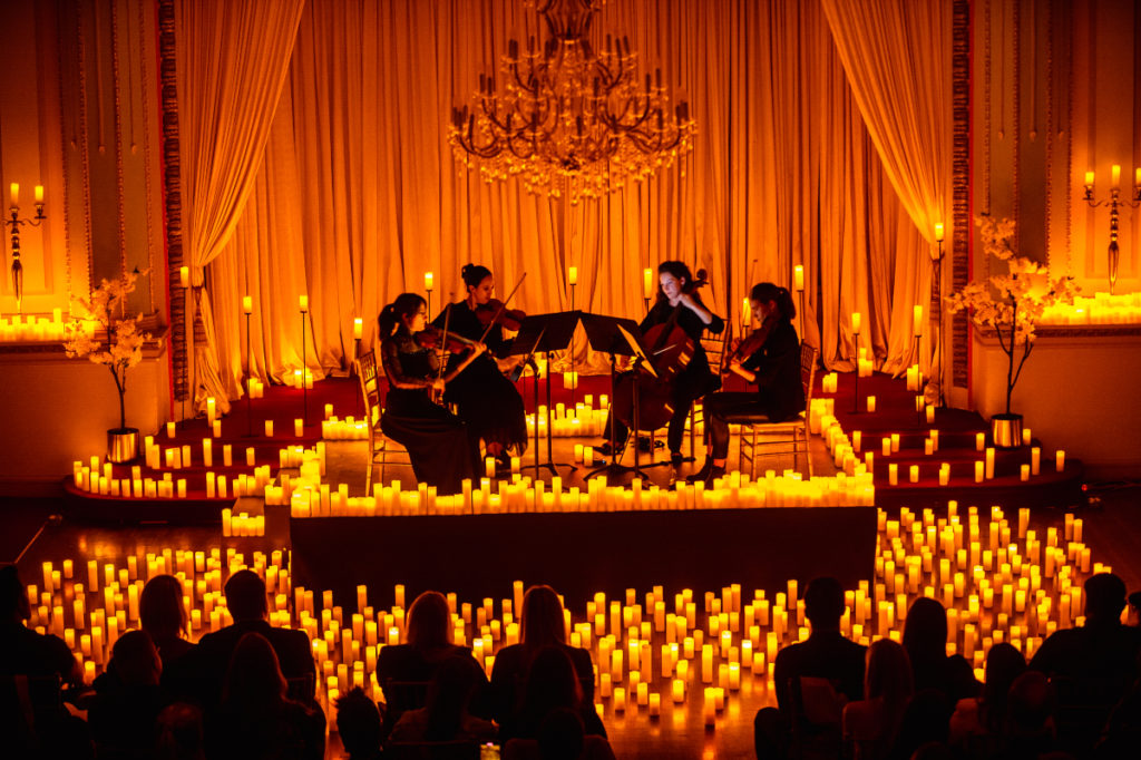 a string quartet performing at under a chandelier at Candlelight Concert in Chicago with people watching in the audience