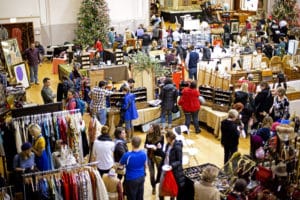 Interior of the holiday market shows festive decor and shoppers browsing booths