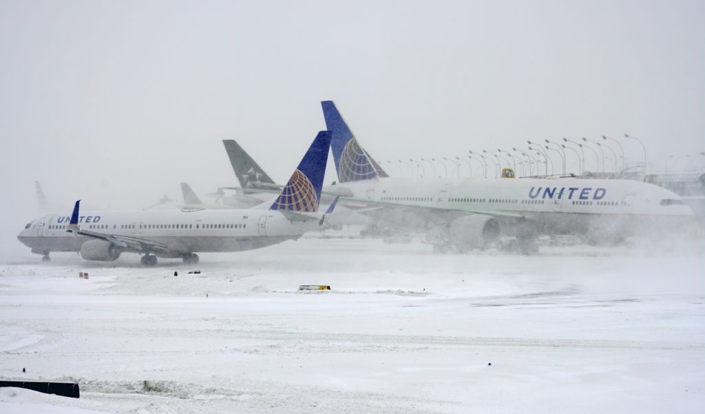 Photo of two planes grounded and surrounded by snow at O'Hare International Airport during a winter storm in Chicago