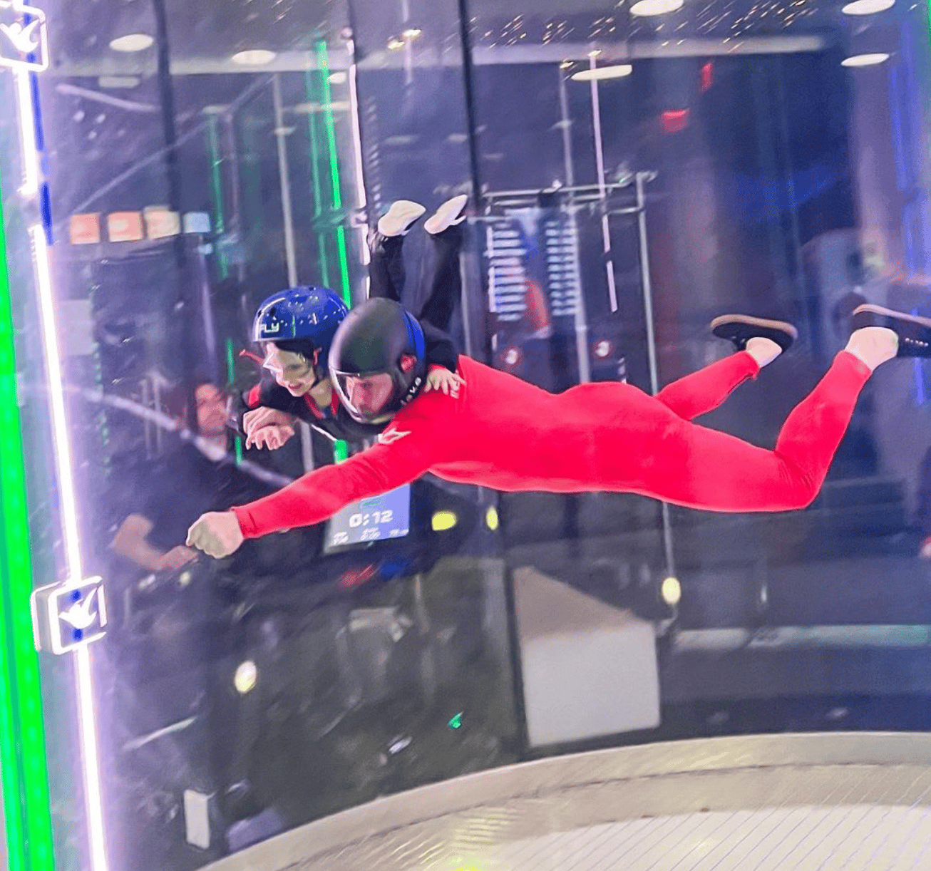 a skydiver instructor and kid with helmets in an indoor skydiving facility 
