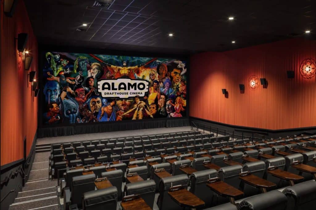 Interior of a movie theater shows seating and a screen.