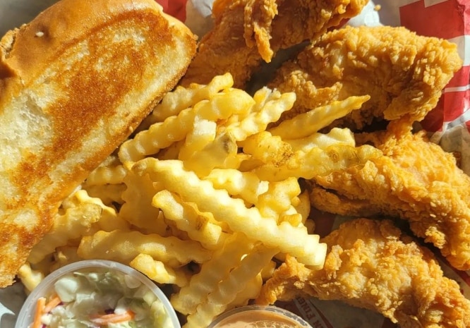 Chicken fingers, fries, toast and slaw pictured in a Raising Cane's basket