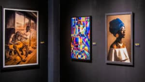 Three paintings pictured on a gallery wall 