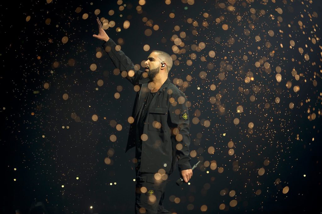 Image showing Drake holding a microphone and waving to a crown at a previous live performance