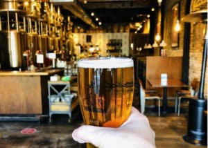 Image showing somebody holding a pint of craft beer at the Corridor Brewery & Provisions craft brewery and restaurant in Chicago’s West Lakeview neighborhood
