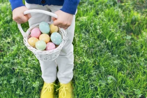 Photo of a kid holding a basket filled with Easter eggs
