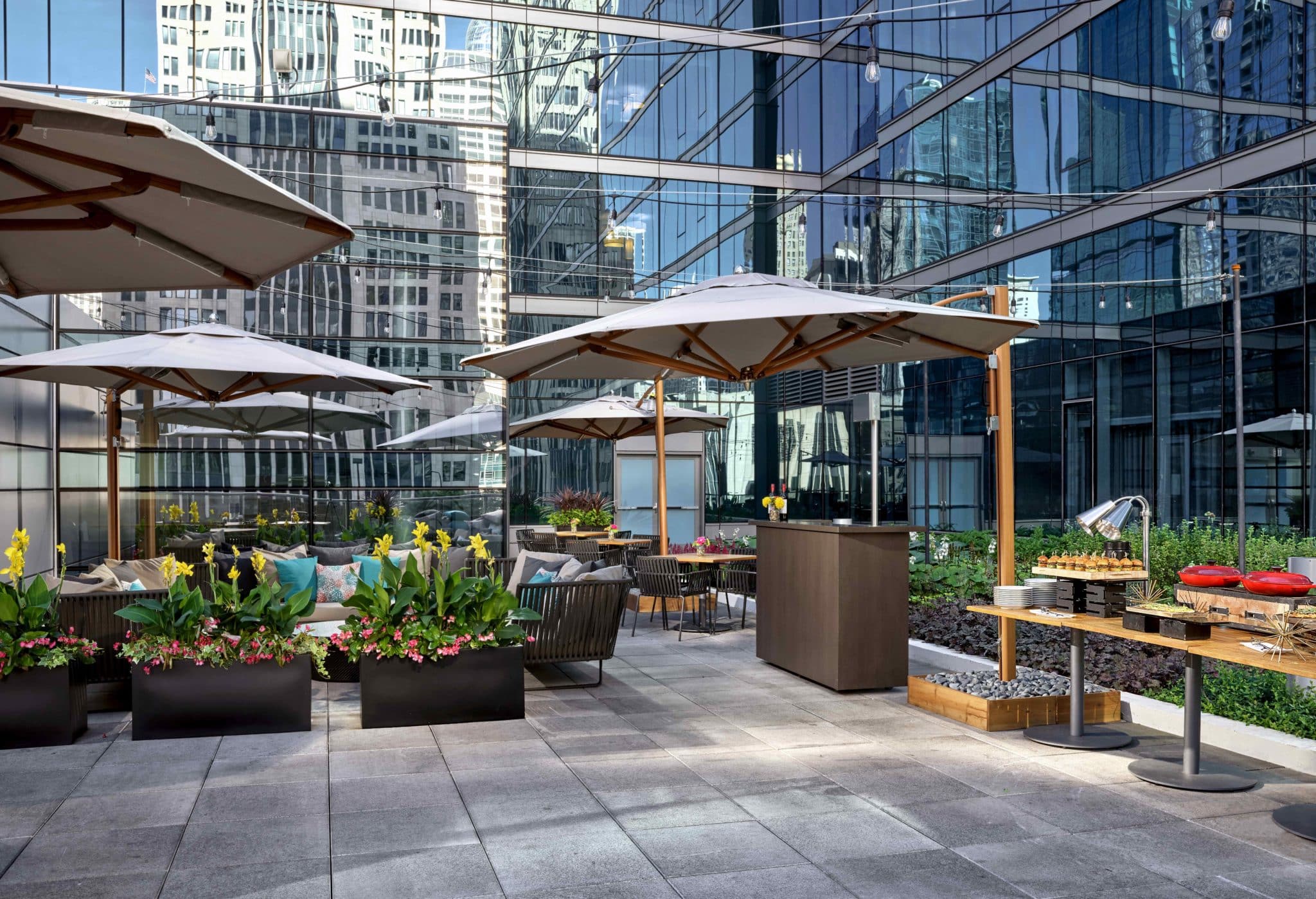 Streeterville social roofptop with suspended lights, greenery, and tables for eating covered by umbrellas 