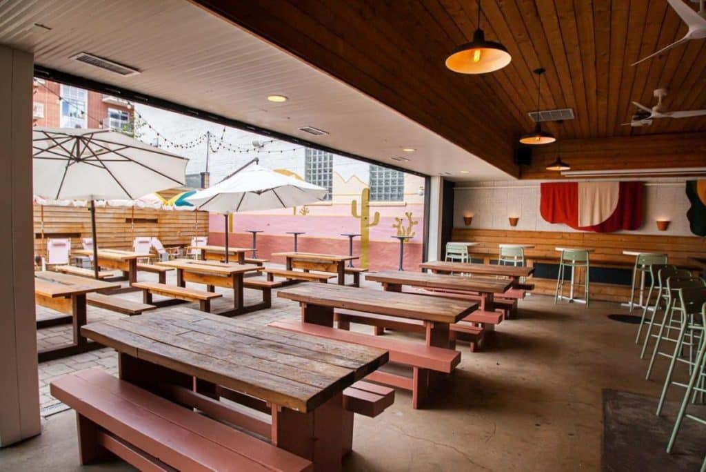 Interior of Sunnygun Chicago in West Loop shows wooden tables and an outdoor patio