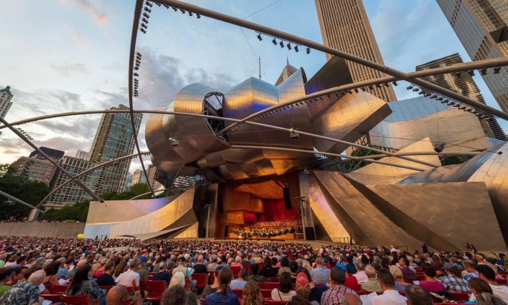 Orchestra performance on the Jay Pritzker Pavilion stage with concert attendees seated