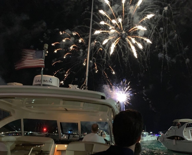 Firework display seen from a harbor as people watch from a boat