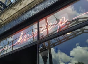 neon pink sign of knee deep outside the store of knee deep vintage in Chicago