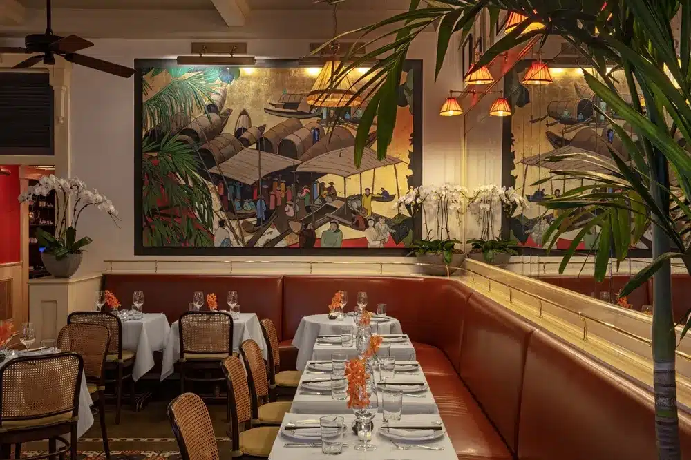large painting hung on the wall with leather boots and dining tables covered in a white cloth with wooden chairs at El Colonial in chicago
