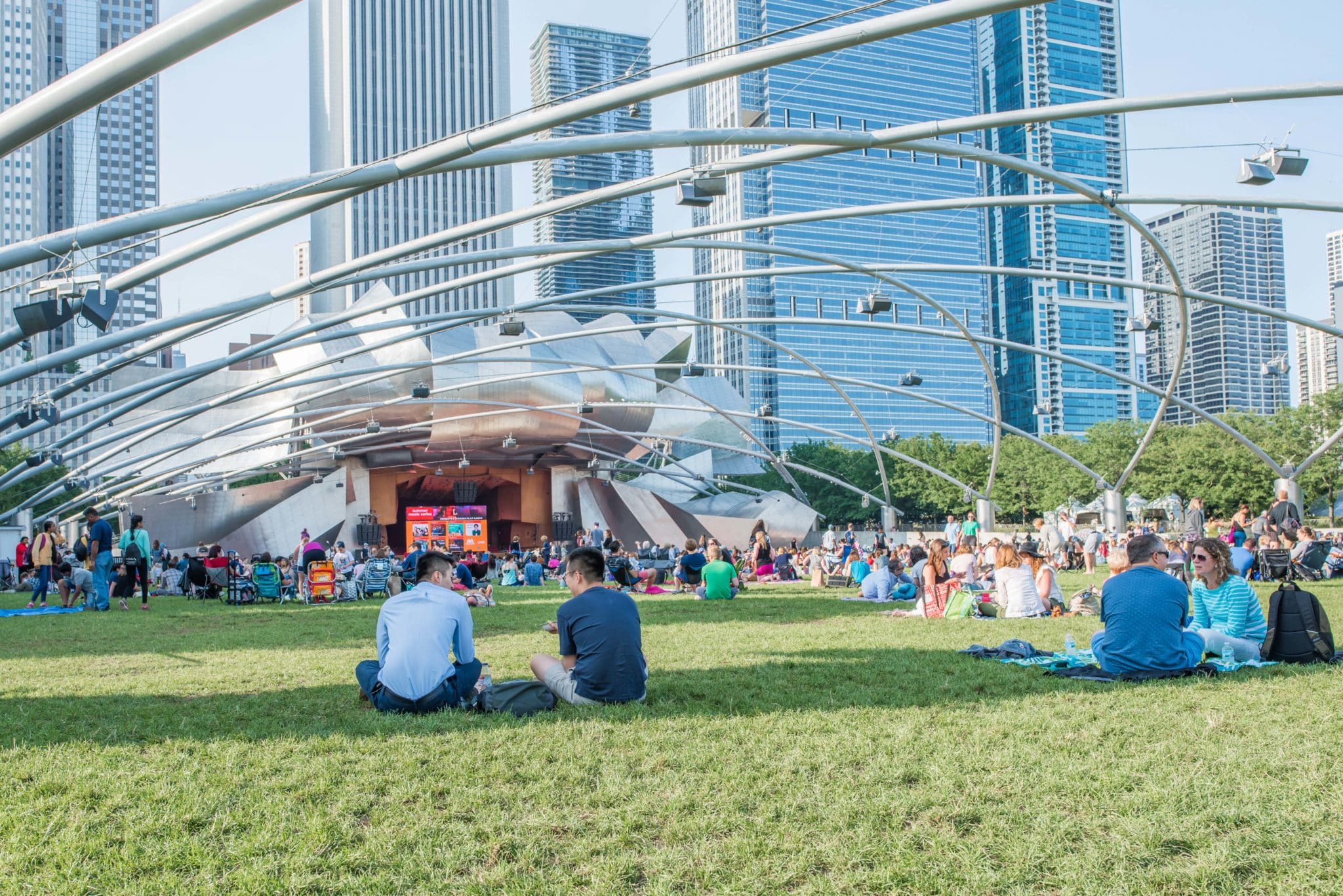 friends sit on the grass at Millennium Park, waiting for a movie to begin. Millennium Park, at Pritzker Pavilion, hosts nightly free movies and concerts during the summer.