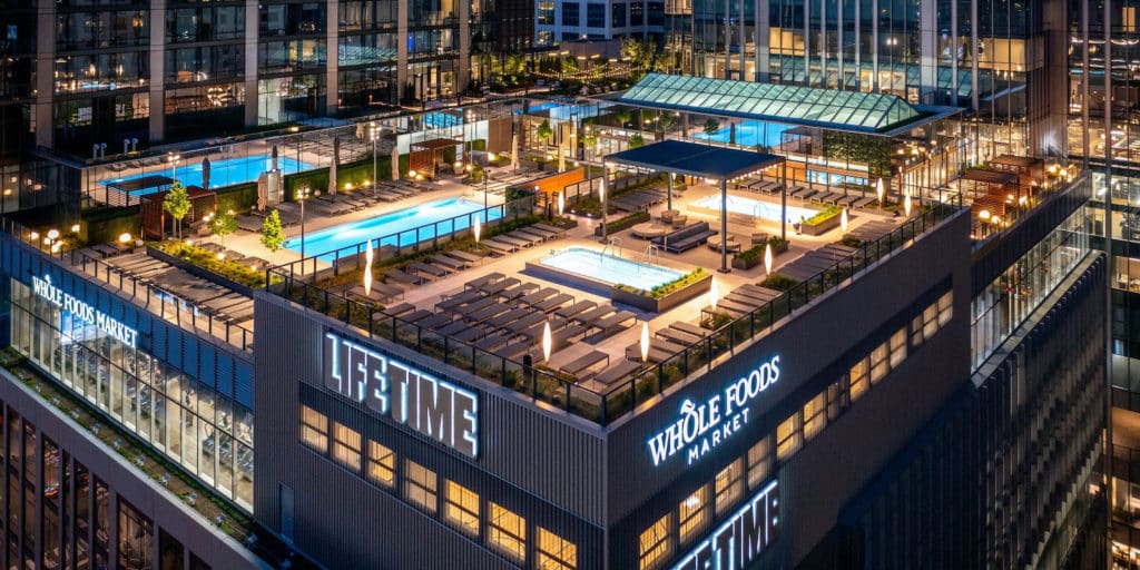 three pools on the deck of whole foods and lifetime with cabanas and lounging chairs at night