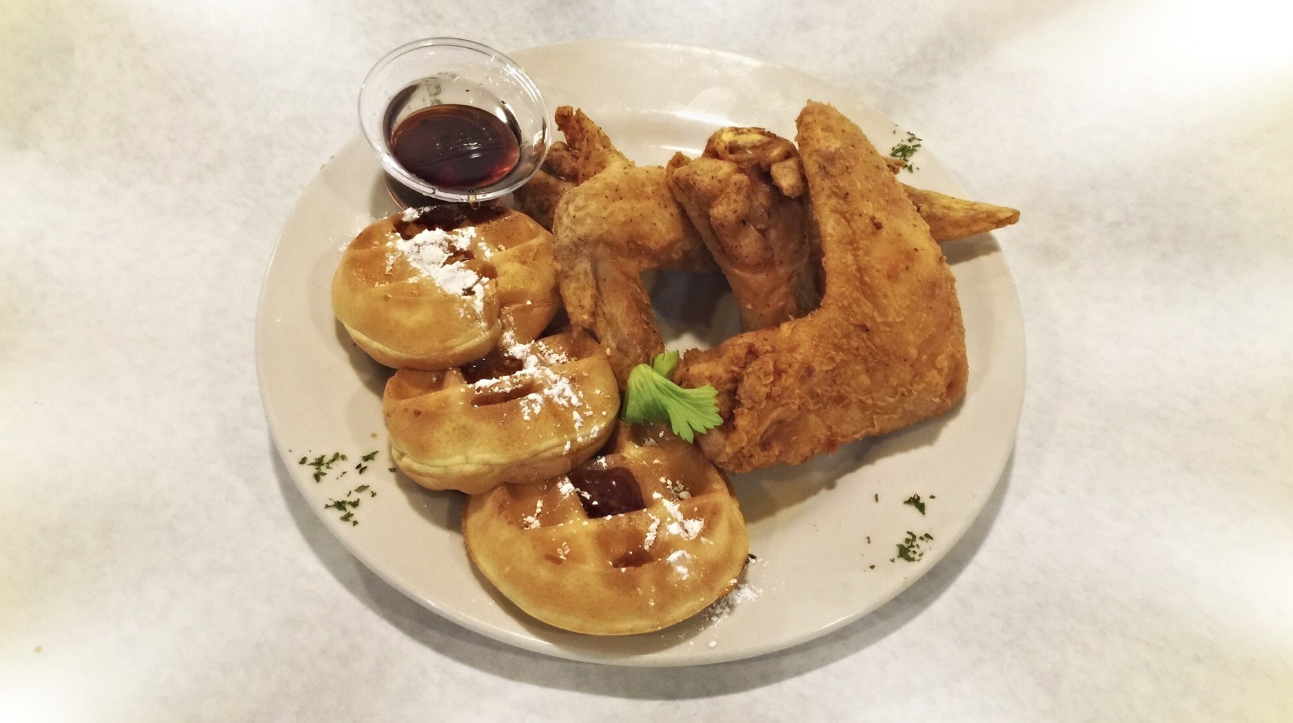 fried chicken, waffles, and syrup served on a plate at pearls place in chicago
