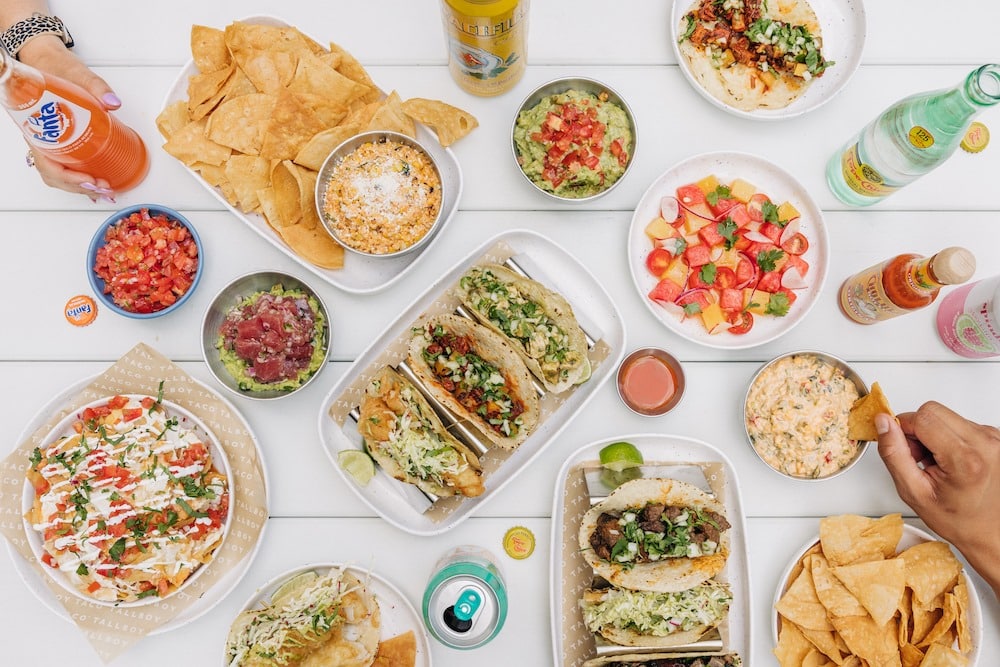 a selection of different tacos, nachos, salsa, and guacamole at Tallboy Taco