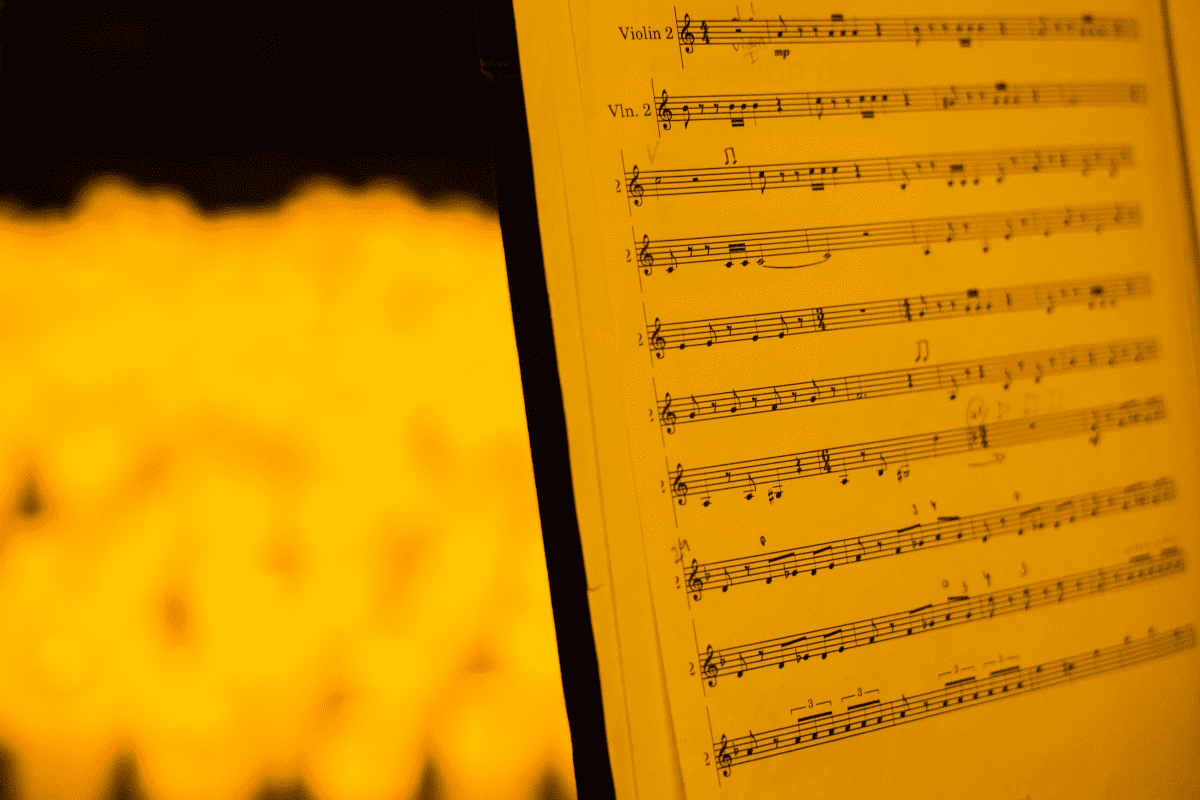 a close up of a music sheet with candles in the background.