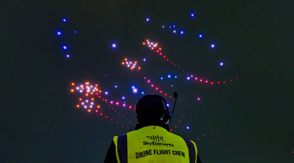 Image showing a man looking up at a drone show in the sky