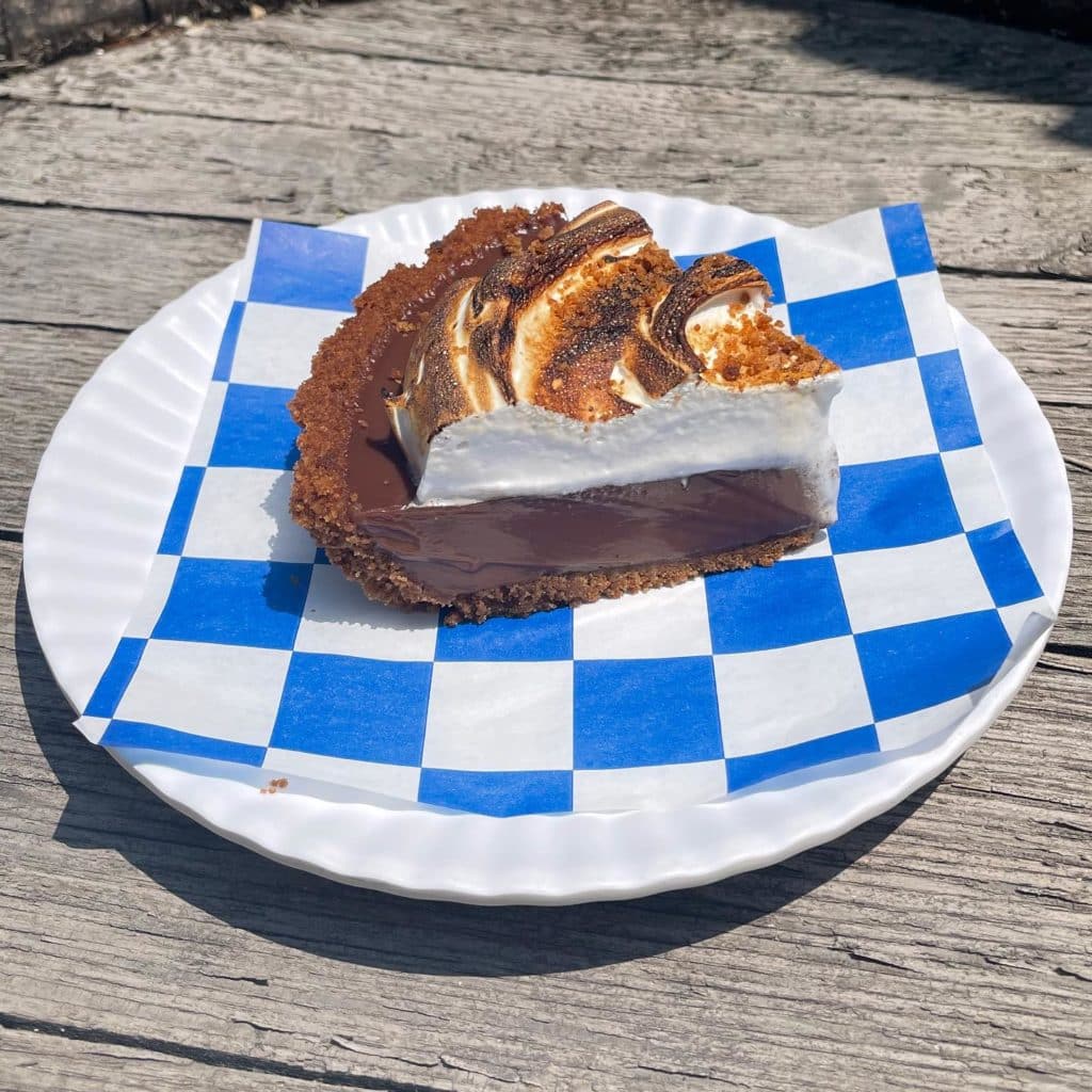 slice of chocolate pie with whipped cream on a blue checker napkin and plastic plate
