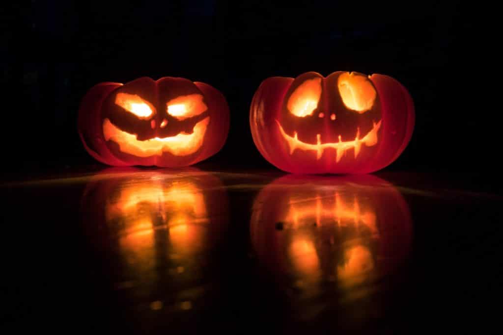 Two carved out pumpkins lit up by candles for Halloween