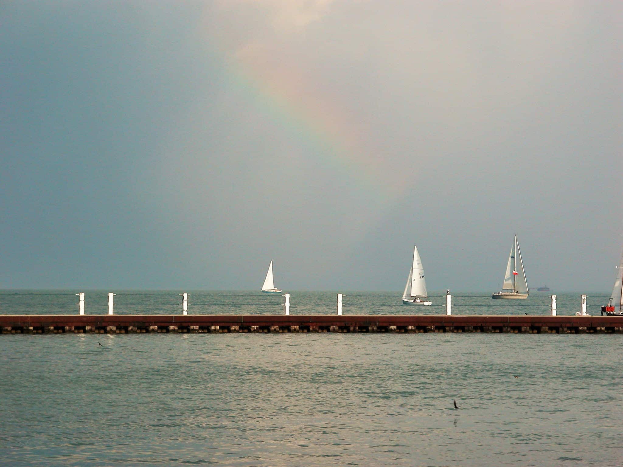 Montrose beach in Chicago with sailboats in the water next to a long pier