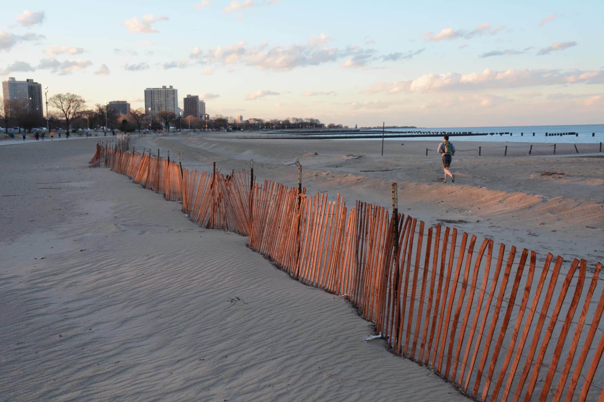 fence along the sand at North Avenue Beach, Chicago with buildings in the back along the water