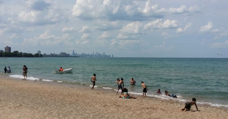 people running on the sand along the shoreline of lake Michigan at Rainbow beach park