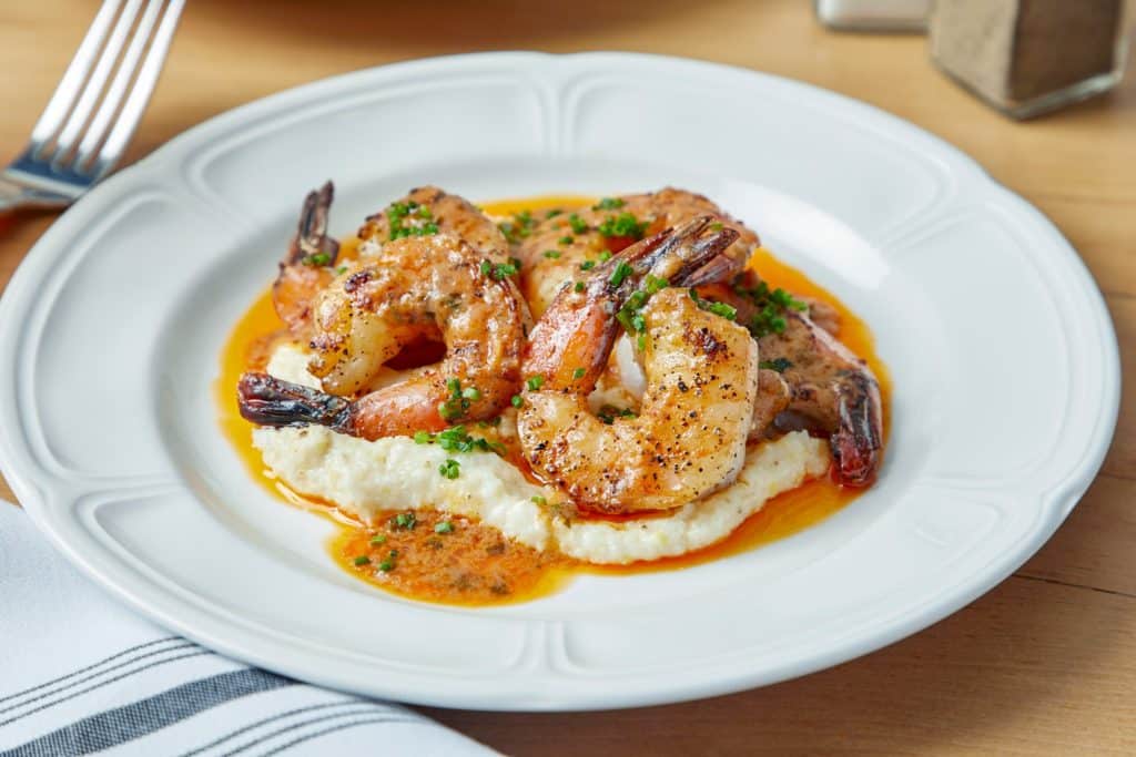 multiple grilled shrimp and grits on a white plate at Roux Diner