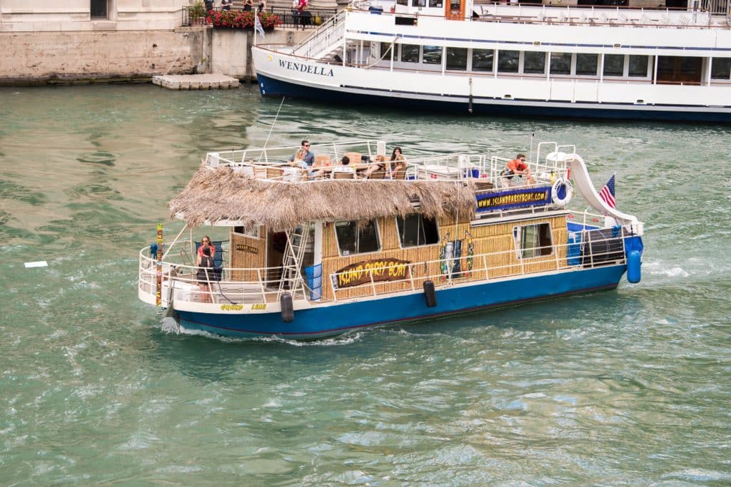 tiki, island themed boat conveys passengers along the Chicago River in summer. The river is always busy with cruises, party boats and other water activities in summer.
