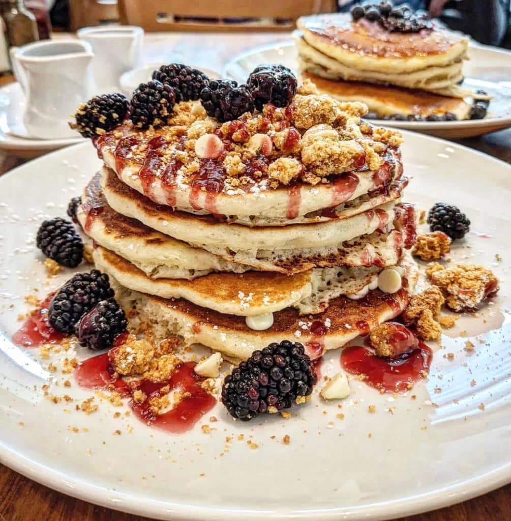 signature pancakes stacked with blackberries and cream at wildberry cafe