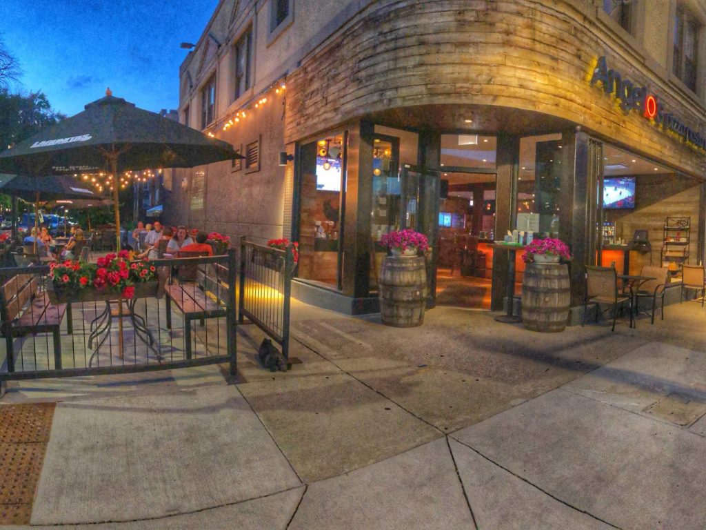 flowerbeds and umbrellas and tables and chairs with suspended lights outside Angelo's wine bar in chicago