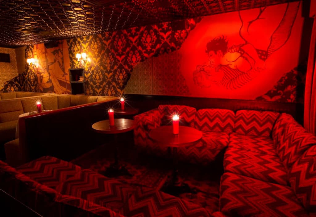 large room dimmed a crimson red with a couch with squiggles and a graphic design on the wall at bordel