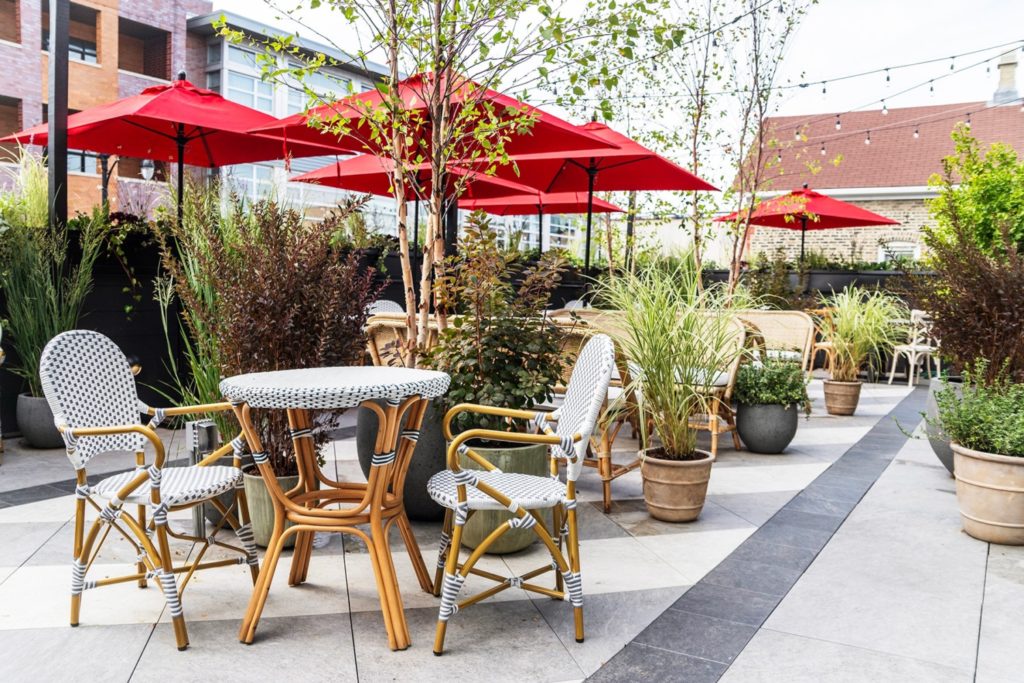 etta rooftop with red umbrellas, plants spread out, and tables and chairs for dining outside